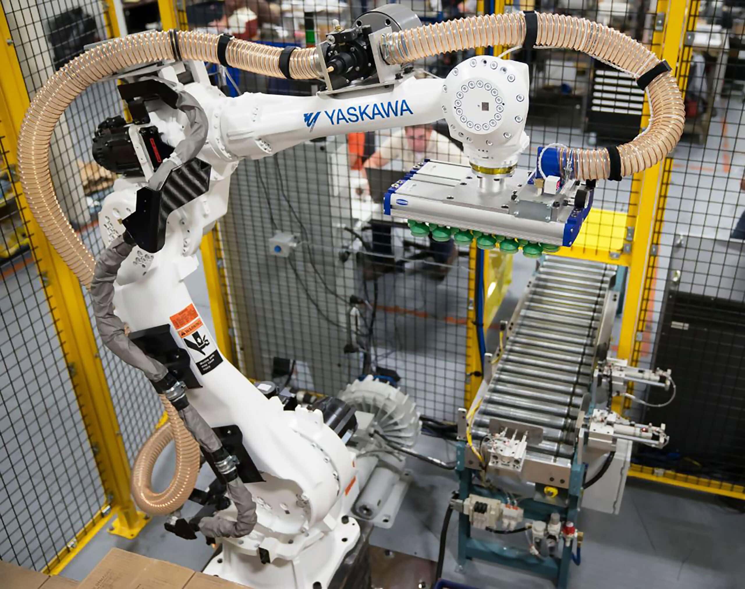 Robotic arm by Yaskawa with advanced end-of-arm tooling, integrated in a palletizing system, demonstrating automation technology in a manufacturing environment.