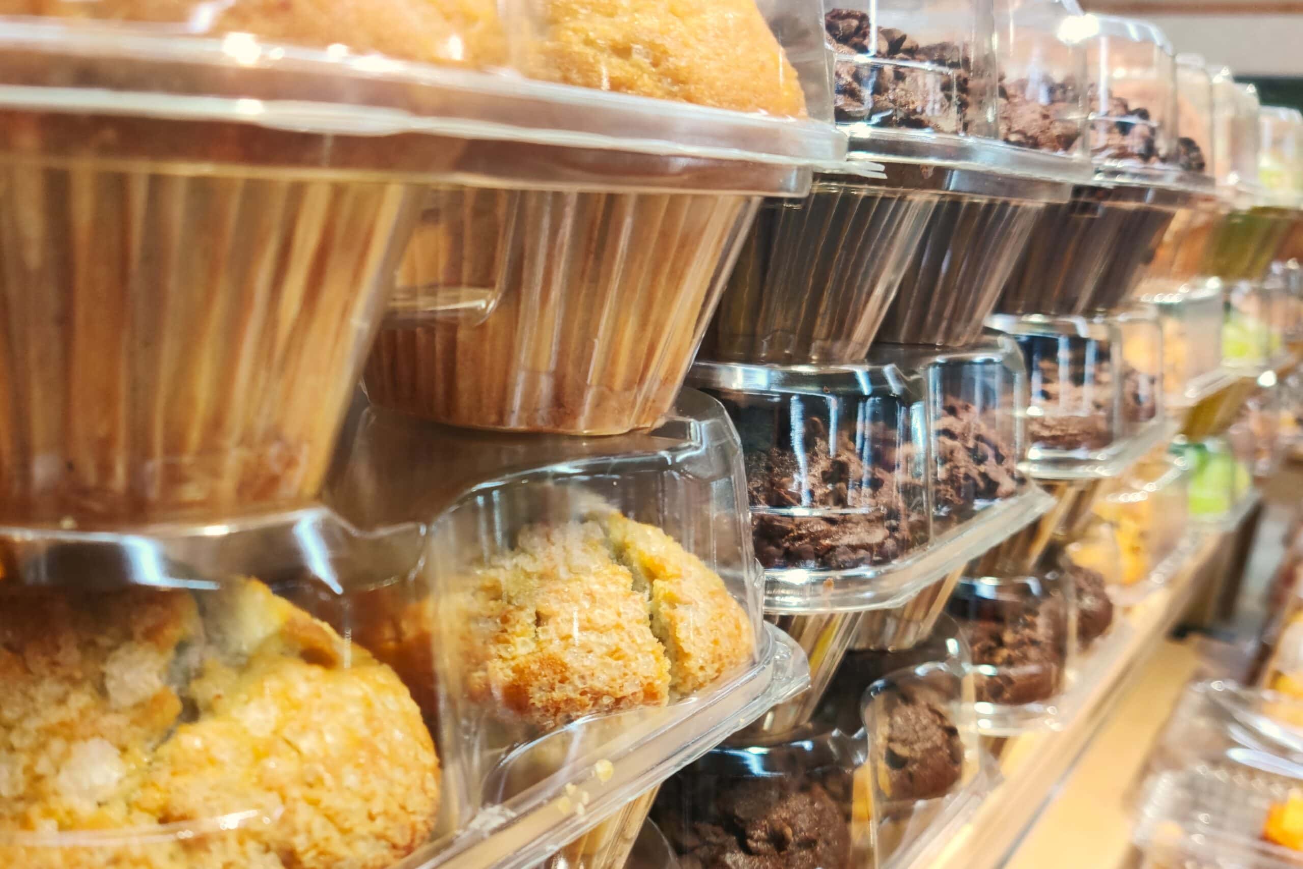 Muffins and baked goods packaged in clear containers, showcasing food and beverage automation for efficient handling and packaging.